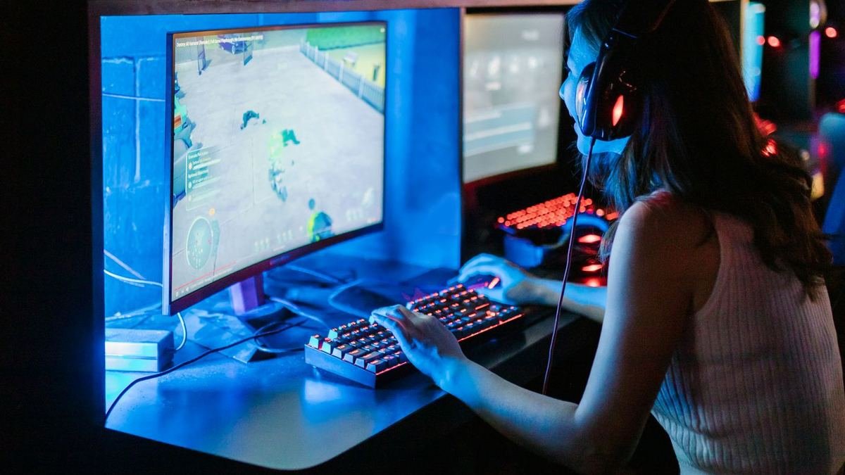 Gamer using headset and keyboard at a PC setup with blue LED lighting
